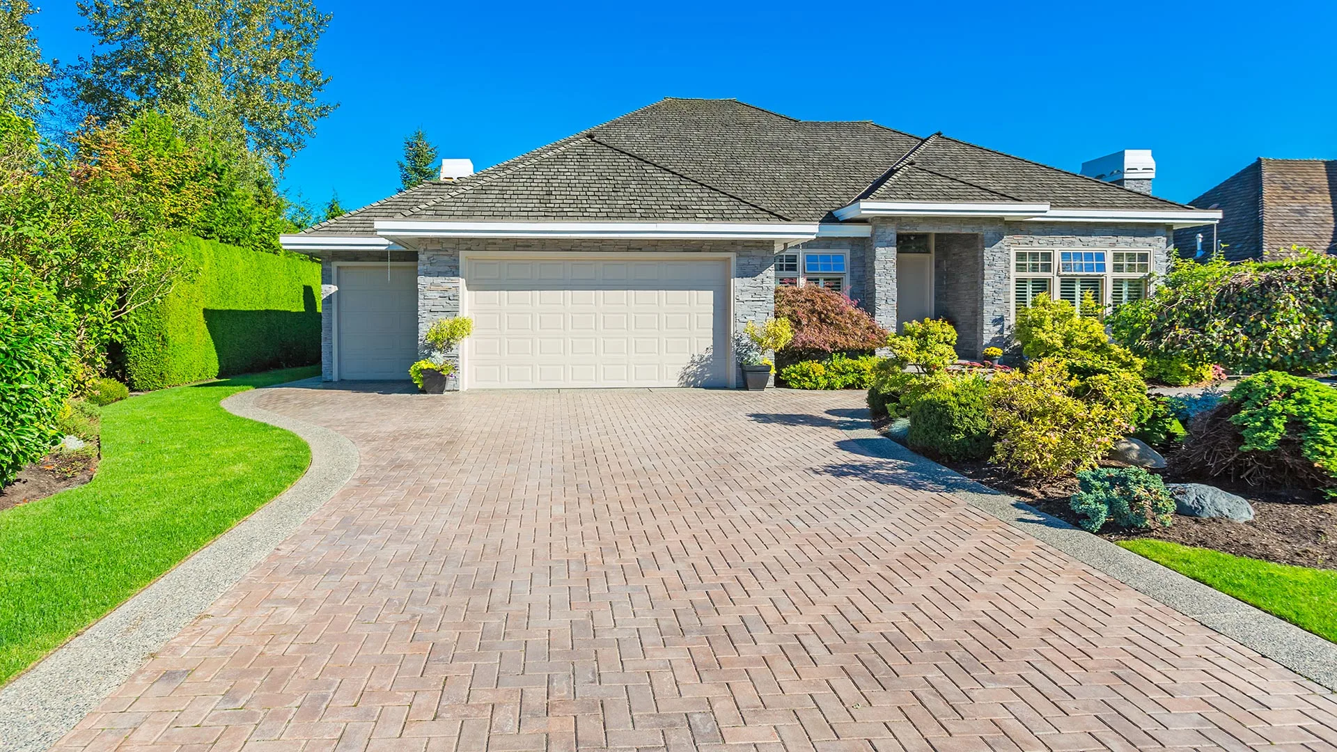 A custom paver driveway installed in front of a home with beautiful landscaping in Bennington, NE. 