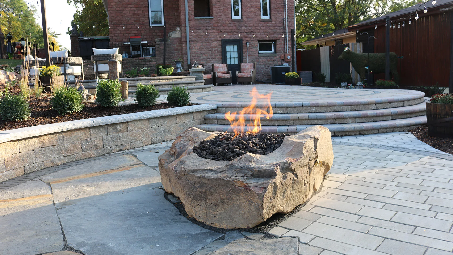 A completed custom design and build project featuring a patio and fire pit behind a home in Chalco, NE. 